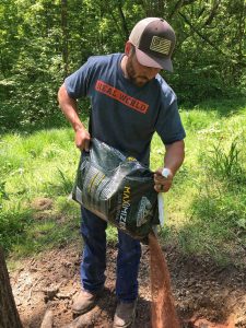 Hunter dumping out custom deer minerals at a mineral site where they are trying to grow big bucks. 